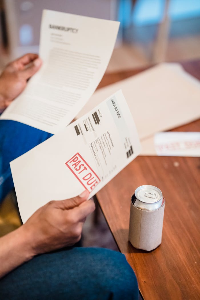 Close-up of a man reading past due notices and bankruptcy papers at a table.